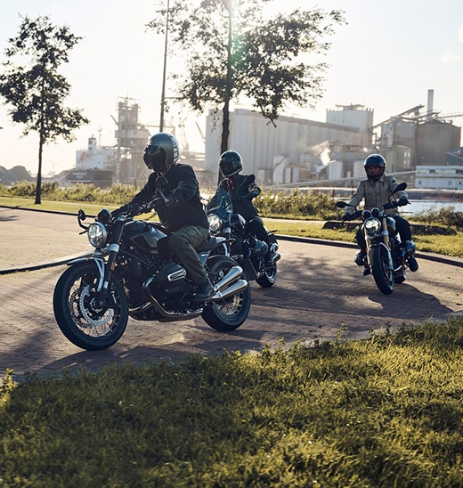 Three people can be seen riding their BMW motorcycles on the road in fine weather.